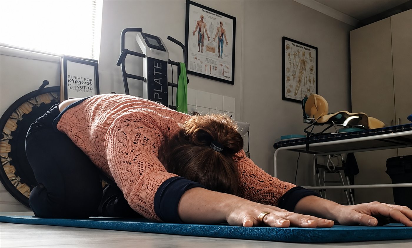 Hélène folded forward in a long resting stretch on the mat